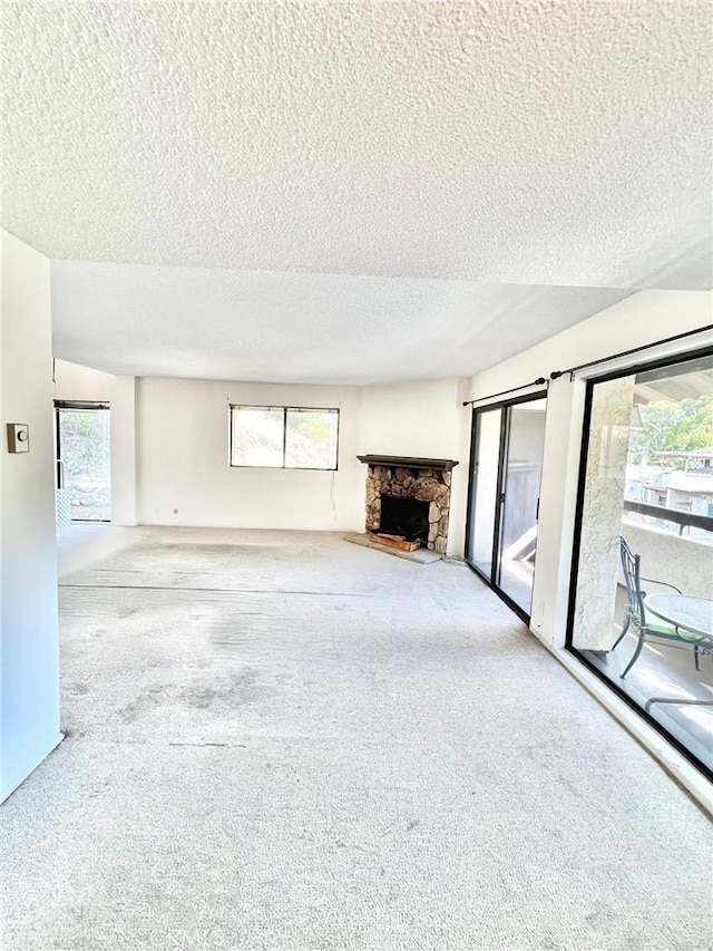 unfurnished living room with a textured ceiling, a fireplace, and carpet floors