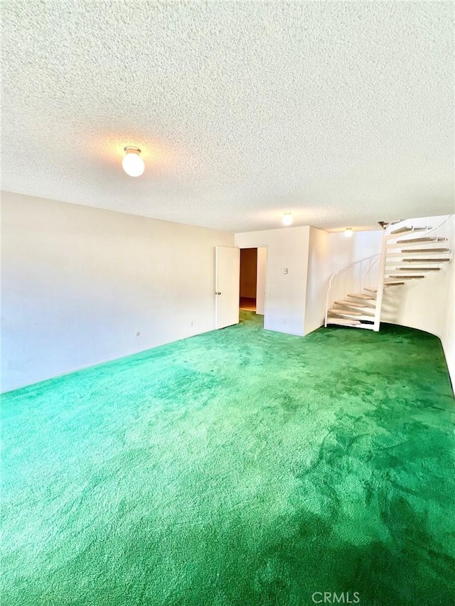 spare room featuring a textured ceiling and dark colored carpet