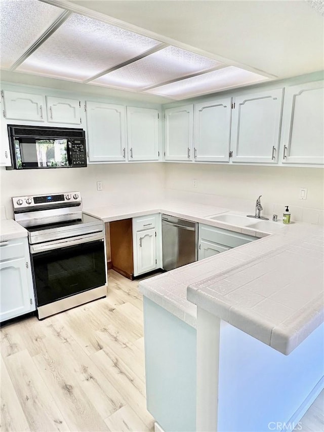 1 Cabrillo Dr, Avalon, CA 90704 - kitchen featuring stainless steel appliances, a sink, light wood finished floors, a peninsula, and white cabinets
