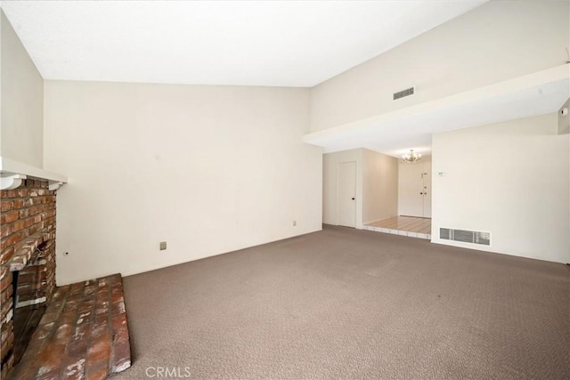 unfurnished living room with carpet floors, a brick fireplace, and an inviting chandelier