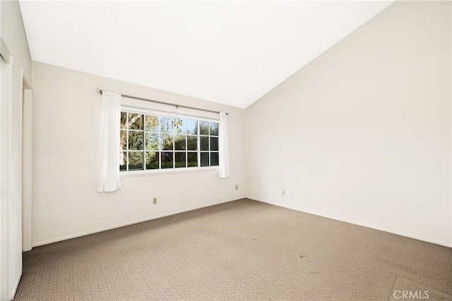 carpeted spare room featuring vaulted ceiling