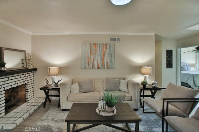 living room featuring hardwood / wood-style flooring, ornamental molding, and a brick fireplace