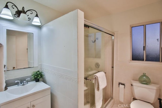 bathroom with vanity, toilet, an enclosed shower, and tile walls