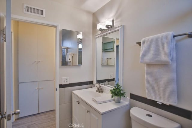 bathroom with vanity, tile walls, and toilet