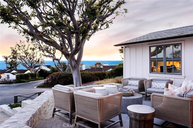 patio terrace at dusk featuring an outdoor hangout area and a water view