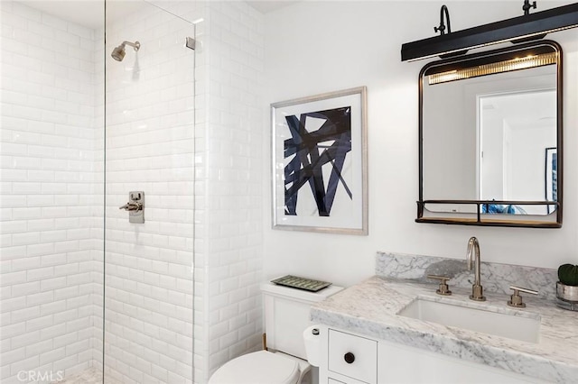 bathroom with toilet, vanity, and tiled shower