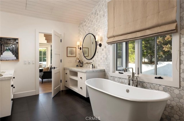 bathroom with a healthy amount of sunlight, a bathtub, and vanity