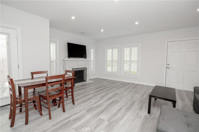 dining room with a brick fireplace and light hardwood / wood-style floors