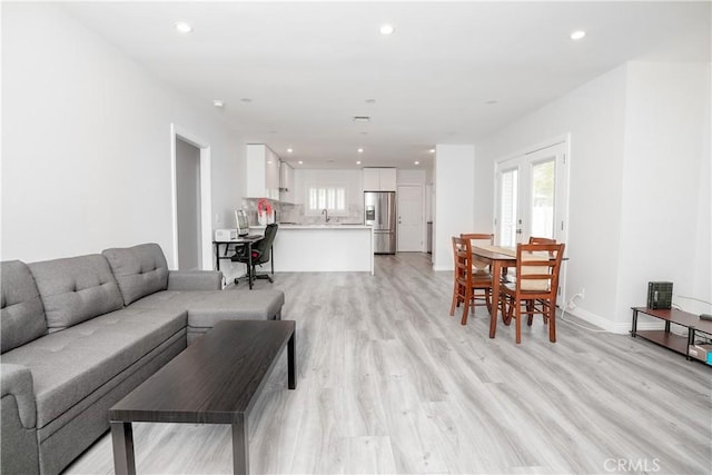 living room with light wood-type flooring, sink, and french doors