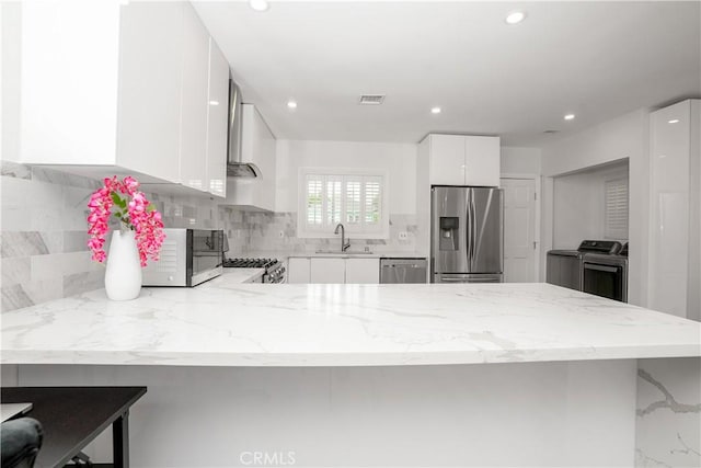 kitchen with a kitchen bar, kitchen peninsula, appliances with stainless steel finishes, white cabinets, and sink