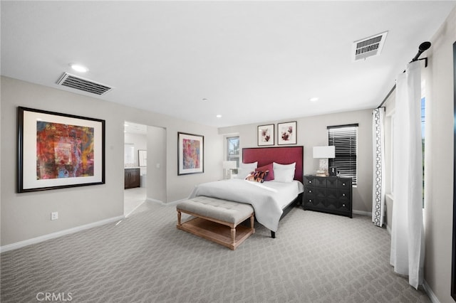 bedroom with ensuite bath and light colored carpet