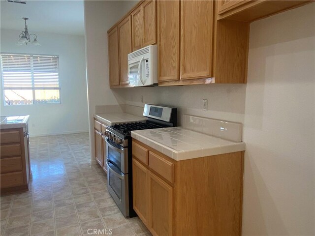 kitchen with range with two ovens, tile counters, a chandelier, and hanging light fixtures