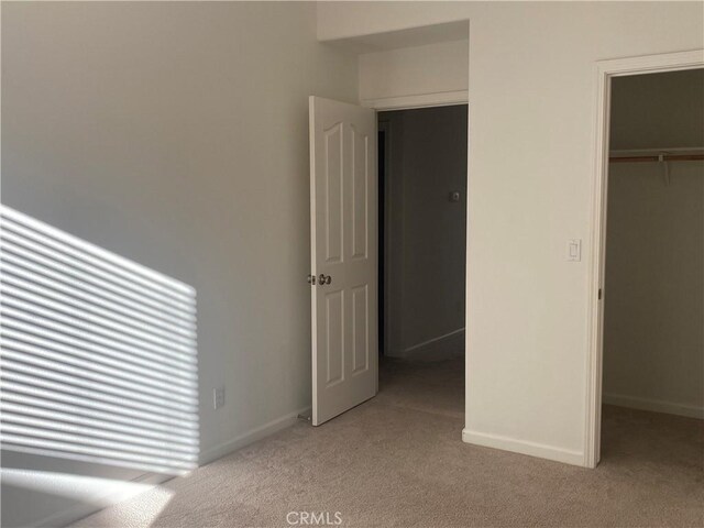 unfurnished bedroom featuring light colored carpet, a closet, and a walk in closet