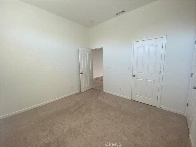 unfurnished bedroom with a closet and light colored carpet