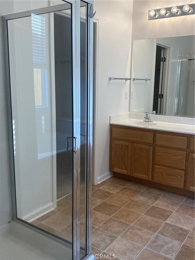 bathroom with a shower with shower door and vanity