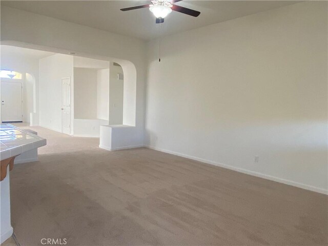 empty room featuring ceiling fan and light colored carpet