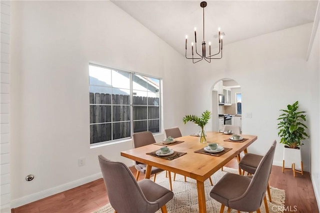 dining space with high vaulted ceiling, hardwood / wood-style floors, and a chandelier