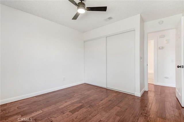 unfurnished bedroom with ceiling fan, a closet, and dark wood-type flooring