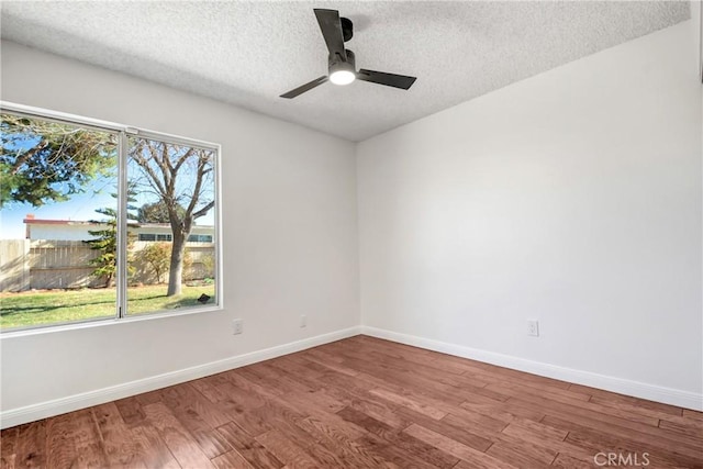 empty room with a textured ceiling, ceiling fan, a wealth of natural light, and hardwood / wood-style flooring