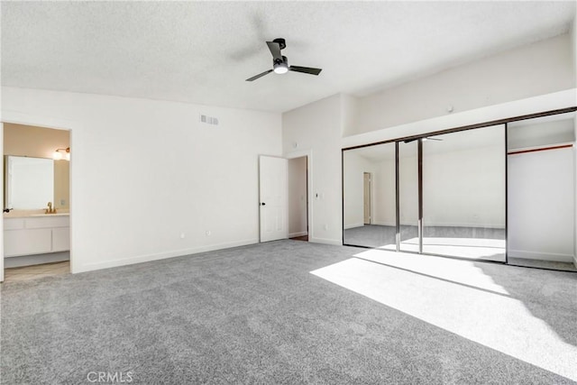 unfurnished bedroom with ensuite bathroom, ceiling fan, carpet flooring, a textured ceiling, and a closet