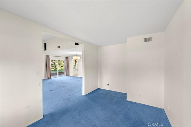 carpeted empty room featuring an inviting chandelier