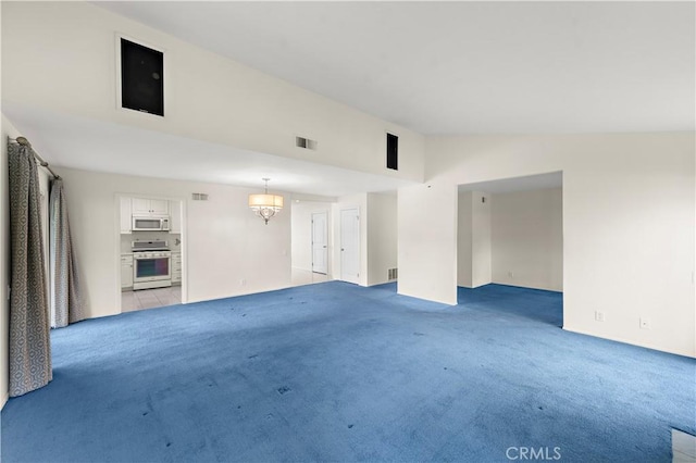 carpeted spare room with a notable chandelier and vaulted ceiling