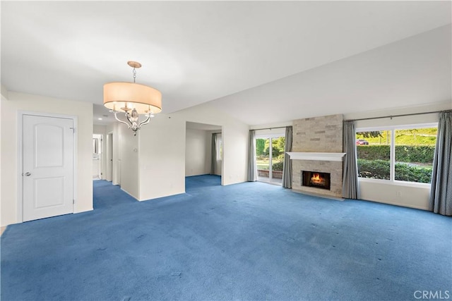 unfurnished living room with an inviting chandelier, a large fireplace, lofted ceiling, and dark colored carpet