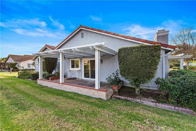 back of house featuring a lawn and a pergola