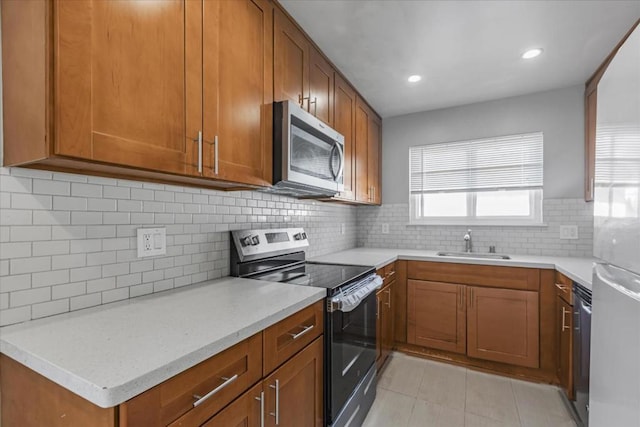 kitchen with light tile patterned floors, appliances with stainless steel finishes, decorative backsplash, light stone countertops, and sink