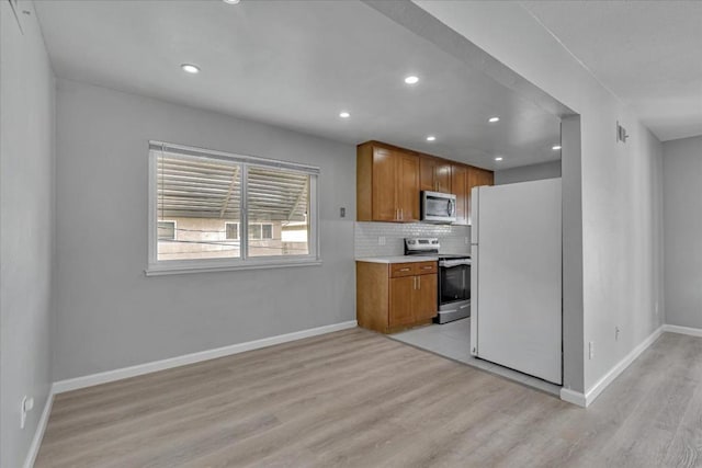 kitchen featuring stainless steel appliances, decorative backsplash, and light hardwood / wood-style floors