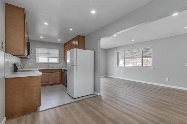 kitchen with tasteful backsplash, appliances with stainless steel finishes, sink, and light hardwood / wood-style flooring