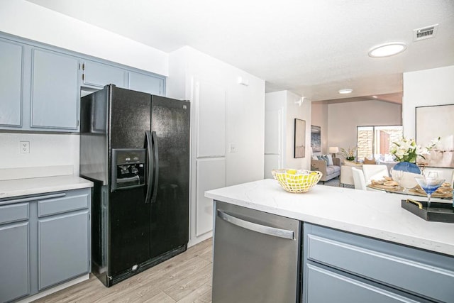 kitchen with blue cabinetry, black refrigerator with ice dispenser, stainless steel dishwasher, and light wood-type flooring