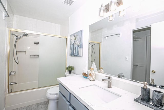 full bathroom with hardwood / wood-style flooring, bath / shower combo with glass door, vanity, and toilet