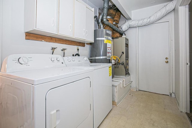 washroom with strapped water heater, washing machine and dryer, and cabinets