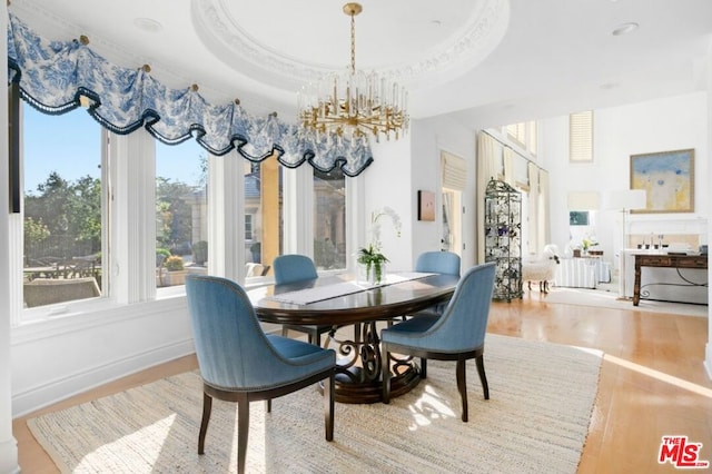 dining area with hardwood / wood-style floors, a raised ceiling, and a chandelier