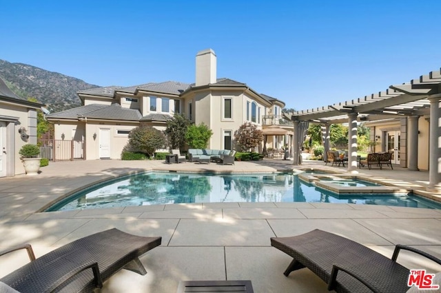 back of property with a mountain view, a swimming pool with hot tub, an outdoor hangout area, and a pergola