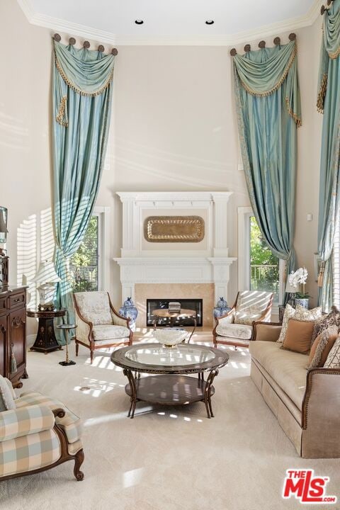 living area featuring light carpet, ornamental molding, and a fireplace