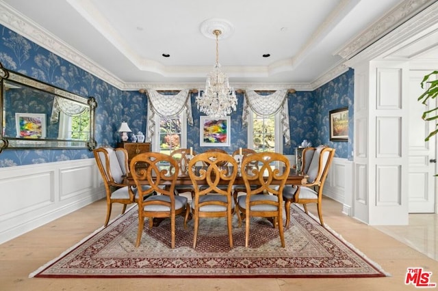 dining room with hardwood / wood-style floors, a raised ceiling, and ornamental molding