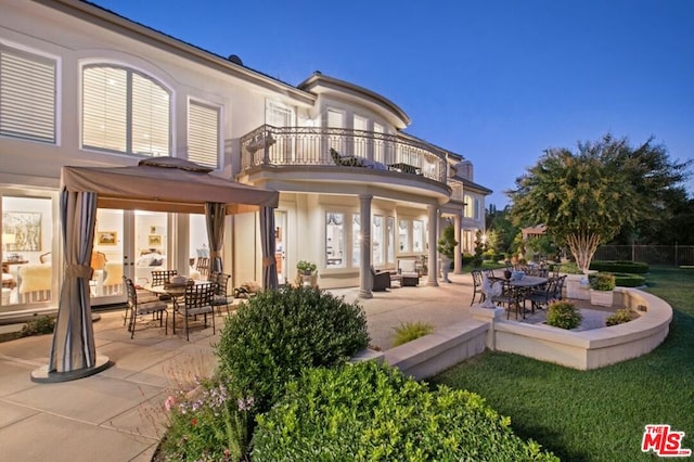 rear view of house with a lawn, a gazebo, a balcony, and a patio