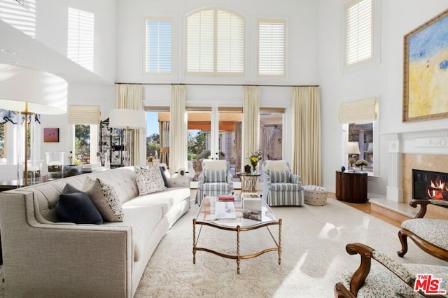 living room featuring a high end fireplace, a high ceiling, and light hardwood / wood-style floors