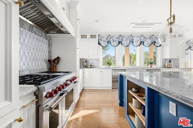 kitchen featuring light stone countertops, appliances with stainless steel finishes, premium range hood, and white cabinetry