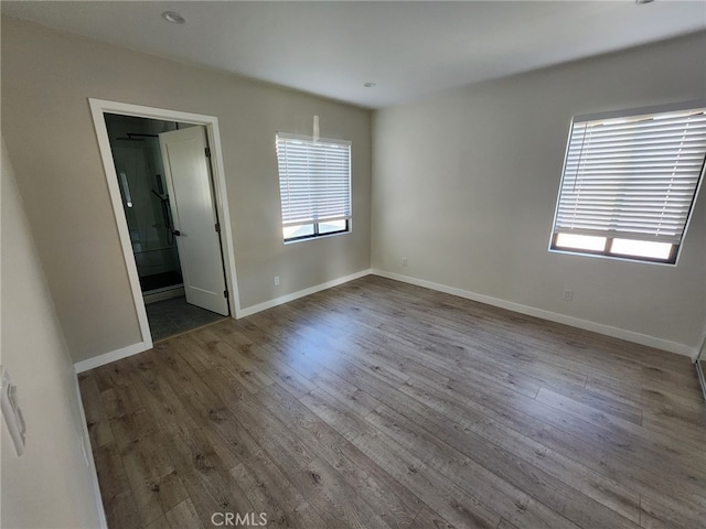 interior space featuring multiple windows, baseboards, wood finished floors, and ensuite bathroom