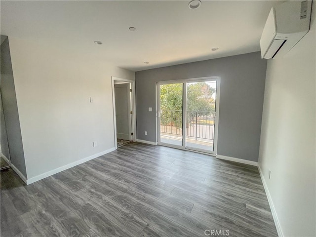 empty room featuring baseboards, wood finished floors, and an AC wall unit