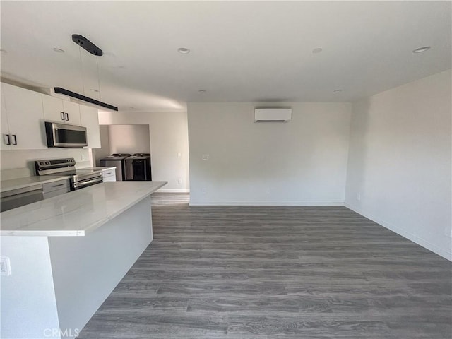 kitchen with washer and clothes dryer, white cabinets, appliances with stainless steel finishes, decorative light fixtures, and a wall mounted air conditioner