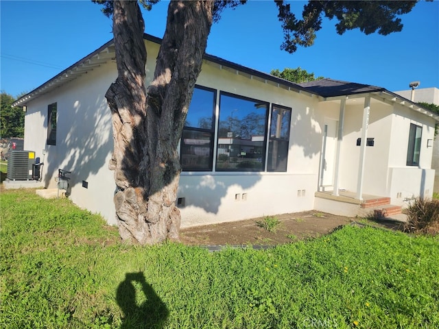 view of side of home featuring crawl space, stucco siding, a lawn, and central air condition unit