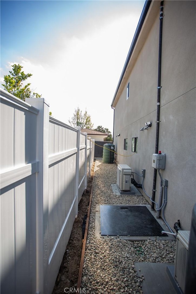 view of side of home with a fenced backyard, cooling unit, and stucco siding