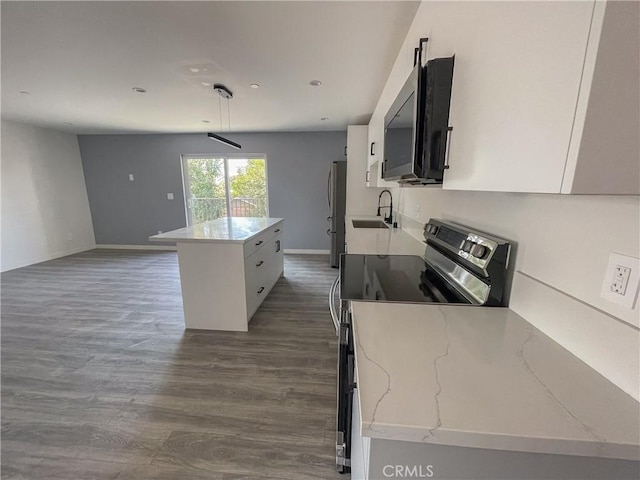 kitchen with dark wood finished floors, a kitchen island, stainless steel appliances, white cabinetry, and a sink