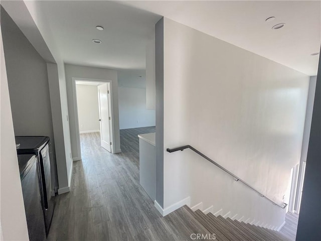 hall with baseboards, wood finished floors, an upstairs landing, and washer and dryer