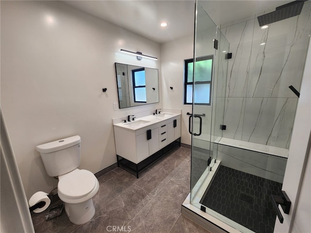 full bath with double vanity, a marble finish shower, toilet, and a sink