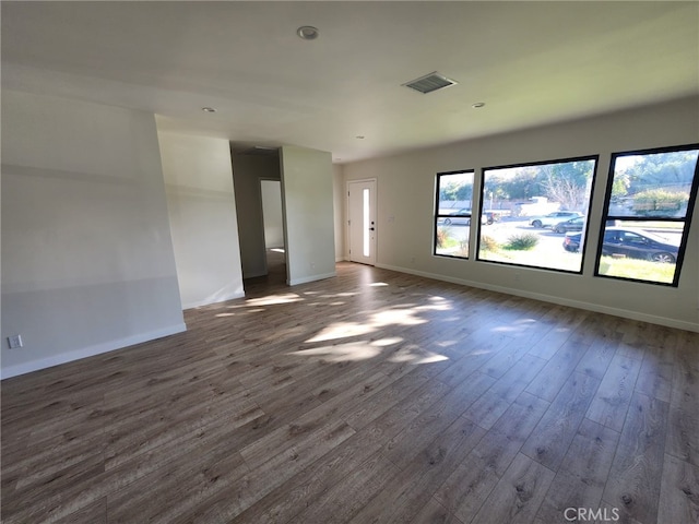 spare room with dark wood-style floors, visible vents, and baseboards